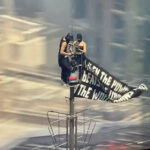 Two people climb to the top of Empire State Building with massive banner